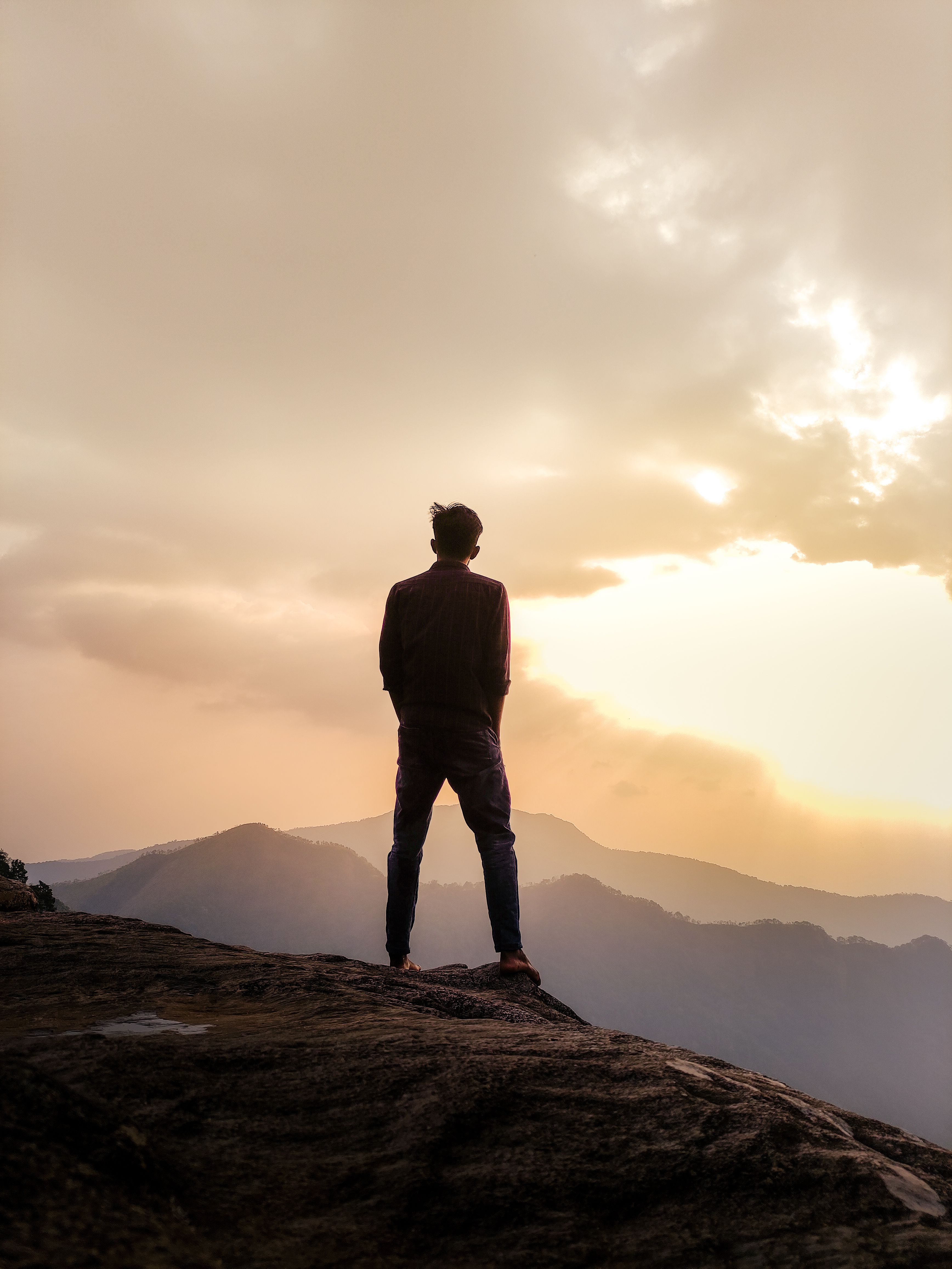 Person standing at sunrise above the mountains